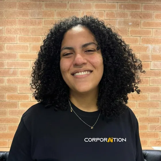Integrante da equipe Corporaition sorrindo, de camiseta preta com a marca