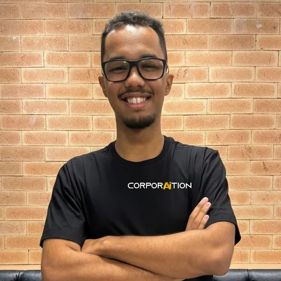 Integrante da equipe Corporaition de braços cruzados, de camiseta preta com a marca
